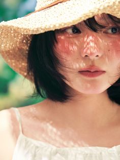 Woman in a straw hat with shadow patterns on her face and shoulders