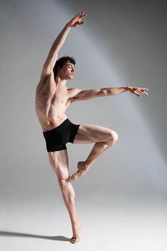 Male ballet dancer in an athletic pose with dramatic lighting in a studio