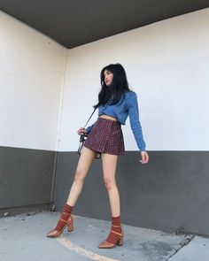 Woman in a plaid skirt and cropped cardigan posing outdoors