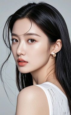 Woman with long black hair and gold earrings in a white top