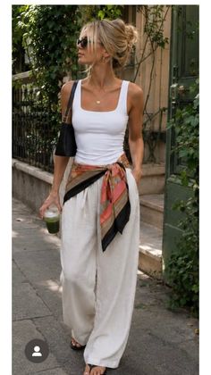 Woman in a white tank top and wide leg pants walking outdoors