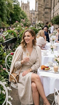 Woman in a beige wrap dress holding a champagne glass at an outdoor cafe