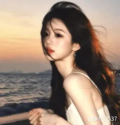 Woman with long dark hair on a beach at sunset with warm lighting