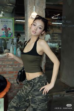 Woman in a crop top and camouflage pants posing indoors