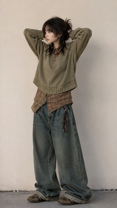 Woman in an oversized sweater and baggy jeans with hands behind her head