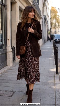 Woman in a brown blazer and floral skirt walking on a city street