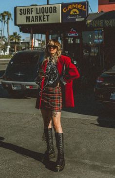 Woman in a red blazer and plaid skirt standing on a street