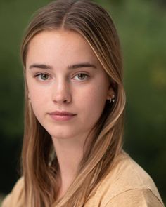 Young woman with long blonde hair and freckles looking directly at the camera
