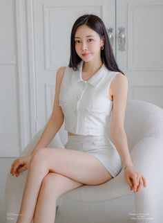 Woman in a white two-piece outfit sitting on a chair indoors