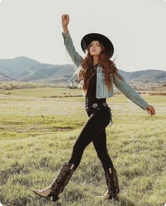 Woman in a cowboy hat and denim jacket walking in a green field