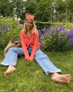 Woman with blonde hair and a bandana sitting barefoot in a garden
