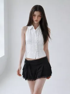 Woman with long dark hair wearing a white halter top and black mini skirt indoors