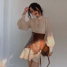 Woman in a long sleeve shirt and leather skirt holding a brown bag