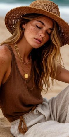 Woman with freckles and a straw hat on a beach with eyes closed