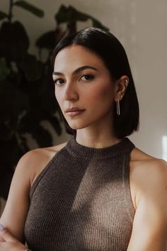 Woman with short dark hair wearing a halter top indoors with soft lighting