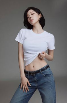 Woman in a white t-shirt and jeans exposing her midriff in a studio