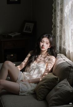 Woman with long hair sitting on a couch in a sunlit room