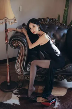 Woman in a black dress and stockings posing on an ornate sofa