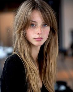 Woman with long blonde hair and blue eyes wearing a black top