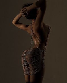 Woman in a chain dress with an exposed back in a provocative pose