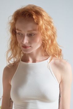Woman with red hair and a nose ring wearing a white top