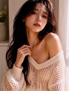 Woman with long hair wearing an off-shoulder sweater and gold necklace