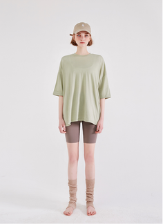 Woman in a baseball cap, oversized t-shirt, biker shorts, and leg warmers