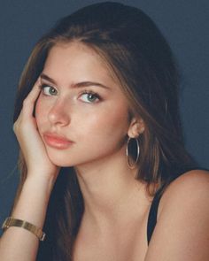 Woman with long hair and green eyes wearing hoop earrings and a gold bracelet