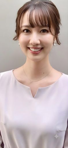 Woman with brown hair and a light top, smiling at the camera