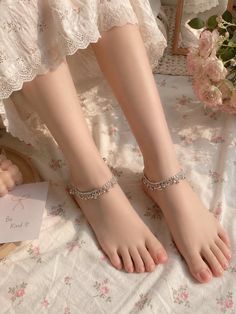 Bare feet with anklets on a floral patterned blanket