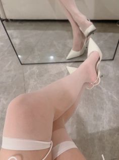 Legs in white stockings and high heels with a mirror reflection