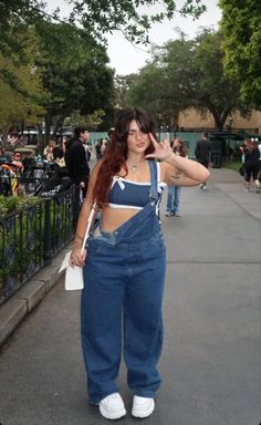 Woman in denim overalls and a crop top posing outdoors