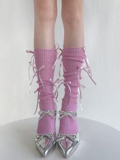 Legs wearing pink socks with ribbons and silver heels with rhinestone bows