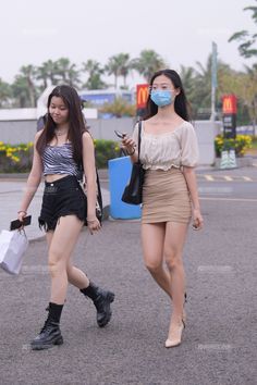 Two young women walking outdoors, one in a mini skirt and the other in denim shorts