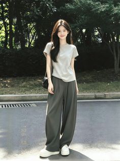 Woman with long dark hair wearing a t-shirt and wide leg pants outdoors