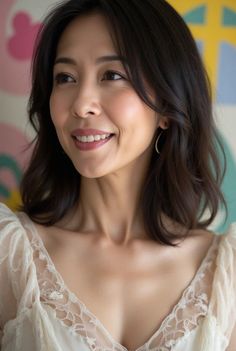 Woman with short dark hair and a lace top smiling indoors