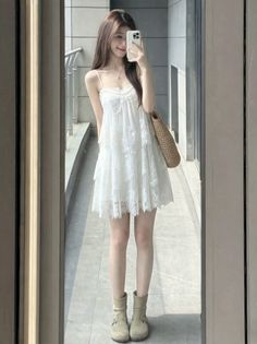 Woman in a white lace dress taking a mirror selfie indoors
