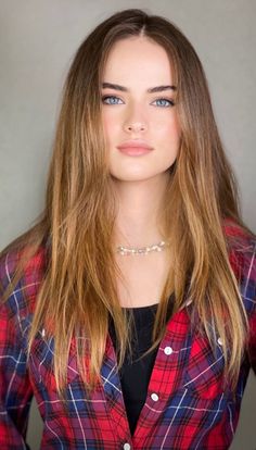 Young woman with long hair and blue eyes wearing a red plaid shirt