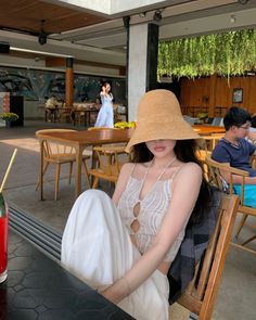 Woman in a straw hat and crop top sitting at a table in a restaurant