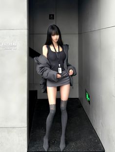 Woman with long black hair wearing a mini skirt and thigh high socks indoors