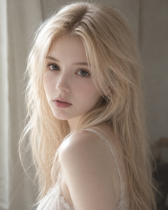 Young woman with long blonde hair wearing a lace top, looking over her shoulder