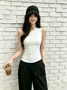 Woman with long black hair wearing a white one-shoulder top and black pants