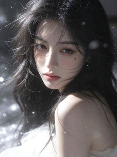 Woman with long black hair and exposed shoulder in soft lighting