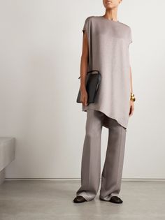 Woman in a tunic top and wide leg pants holding a clutch bag