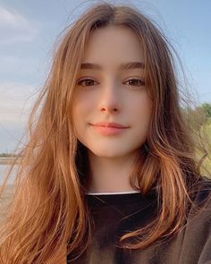 Young woman with long brown hair wearing a black shirt outdoors