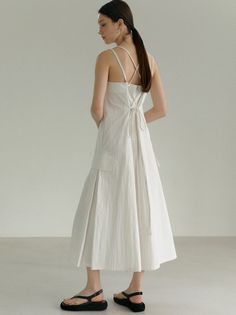 Woman in a white dress with a ponytail standing indoors