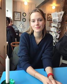 Woman with long hair wearing a blue sweater sitting at a blue table in a cafe
