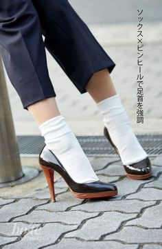 Lower body of a person wearing high heels with white socks and cropped pants outdoors