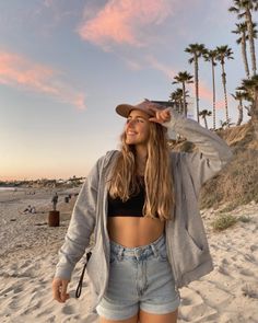 Young woman in a crop top and shorts on a beach at sunset