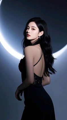 Woman in a black backless dress with long dark hair against a dark background